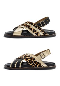 Sandales plates avec semelles noires, brides croisées en métal doré et imprimé léopard, boucles réglables à la cheville, vues de côté.