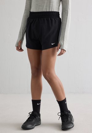 Schwarze Sportshorts mit elastischem Bund, kombiniert mit einem hellgrauen Langarmshirt sowie schwarzen Sportschuhen und Socken.