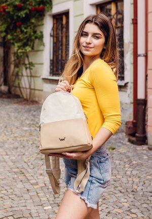 Beige and cream backpack with rounded top, front zip pocket, and logo. Textured fabric with stitching details; adjustable straps.