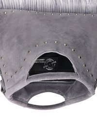 Sac à main en suède gris avec une poignée arrondie, des accents cloutés et un dessus ouvert révélant un intérieur noir et un compartiment zippé.