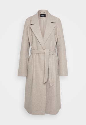 Manteau long en laine beige clair pour femme, avec de larges revers et une ceinture en tissu nouée à la taille, sur fond blanc.