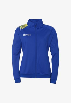 Blå sportsjakke med lynlås foran, høj krave og kontrasterende gul geometrisk mønster på den ene skulder. Logoet "Kempa" trykt i hvid.