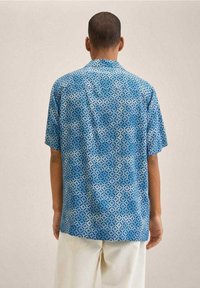 Korte mouwen blauwe shirt met een patroon van diamanten in verschillende tinten. Lichtgewicht stof, ontspannen pasvorm, met een gewone kraag en rugpand.