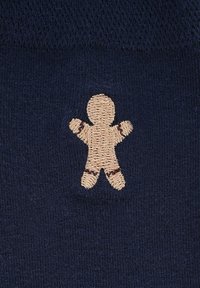 Granatowa skarpeta z haftowanym beżowym piernikiem z brązowymi akcentami na ramionach i nogach. Miękki, teksturowany materiał.