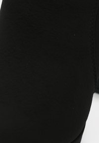 Juodas zomšinis kulkšninis botas su lygiu paviršiumi ir prigludusia siluetu. Yra suapvalinta nosis ir šoninėmis siuvimo detalėmis.