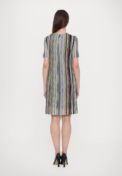 Rochie până la genunchi cu mâneci scurte, având dungi verticale multicolore din texturi diferite. Pantofii cu toc negri completează aspectul.