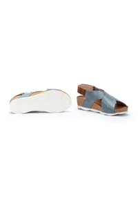Sandalias de cuña azules y marrones con diseño de tiras cruzadas, plantilla de corcho y suela de goma blanca; la textura es suave y mate.