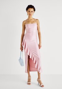 Ροζ σατέν φόρεμα με κοτσίδα, λεπτές τιράντες, λεπτομέρεια με ρυτίδες στη πλευρά, ψηλή σχισμή και λεία υφή. Συνδυασμένο με μια ανοιχτό γαλάζια τσαντάκι με χάντρες.