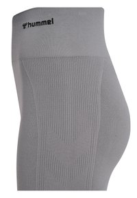 Grijze leggings met een textuurband met het Hummel-logo; verticale en chevron ribbelpatronen op de benen. Zacht, rekbaar materiaal.