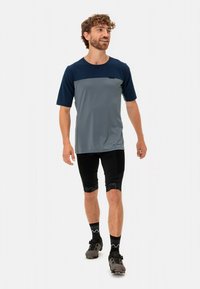 Herres utendørs skjorte i grått og marineblått, med korte ermer og rund hals; kombinert med svarte sykkelshorts og solide grå sko.