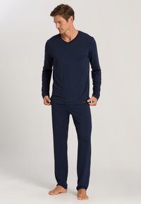 Navyblauwe langarm V-hals top en bijpassende broek van een soepele, lichte stof. Minimalistisch ontwerp met een subtiele merklabeldetail.