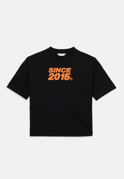 T-shirt noir à manches courtes avec texte orange "SINCE 2015" imprimé sur la poitrine, présenté sur un fond clair uni.