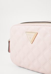Pink quilted synthetic leather bag with a gold triangular logo. Features a zipper closure and accent stitching along the diamond pattern.