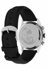 Montre Timex avec un boîtier en acier inoxydable, un bracelet en caoutchouc noir et des détails en argent. L'arrière présente un globe et des informations sur la marque.