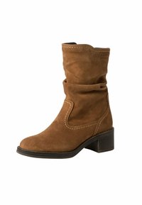 Botín de ante marrón hasta el tobillo con un diseño aflojado, punta redondeada y un tacón bajo en bloque. Presenta costuras en contraste y una textura suave.