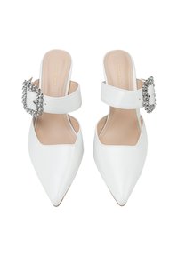 Chaussures slingback blanches à bout pointu avec une large sangle ornée d'une boucle en cristal décorative. Texture en cuir lisse avec une semelle intérieure beige.