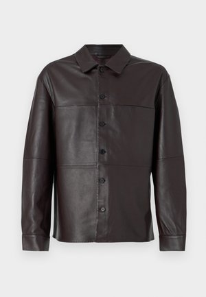 Camisa de cuero marrón con botón en la parte delantera, cuello puntiagudo, mangas largas y paneles sin costuras para un diseño limpio y estructurado.