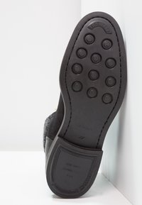 Schwarze Gummisohle mit runden Grip-Mustern, strukturierter grauer Oberteil, gekennzeichnet mit "EST 1949" und "GANT" an der Ferse, Größe 37.