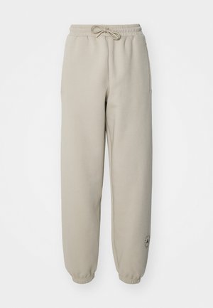 Beige joggingbroek met een elastische tailleband en trektouw, voorzien van zijzakken en een logo-detail op het onderbeen. Geweven stof.