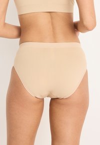 Beżowa bielizna bezszwowa o gładkiej fakturze i elastycznym pasku, z wysokim stanem i minimalnymi detalami szwów.