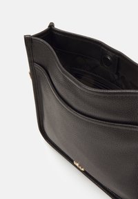 Borsa a spalla in pelle nera con finitura testurizzata, dotata di apertura superiore, scomparto interno e dettagli in metallo dorato.