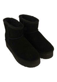 Botines de ante negro con un interior suave y aterciopelado, puntera redondeada y suela plana de goma con relieve. Sin hardware ni acentos visibles.