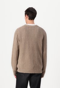 Beige kötött pulóver, bordázott textúrával, kerek nyakkivágással és hosszú ujjal, laza fazonnal és egyenes aljú kialakítással.