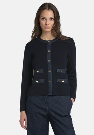 Tmavomodrý sveter na gombíky s džínsovými detailmi, okrúhlym výstrihom, zlatými gombíkmi na prednej strane a dvoma náprsnými vreckami so zapínaním na gombíky.