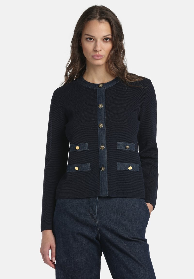 Tengerészkék kardigán farmer részletekkel, kerek nyakkivágással, elöl arany gombokkal és két patentos zsebfedéllel.