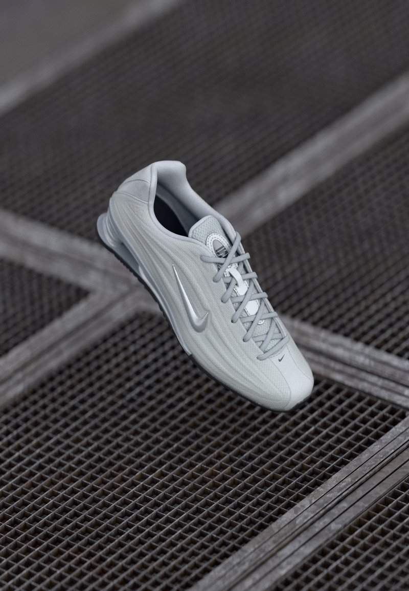 Heledad hallhalli Nike'i tossud lipsudega, millel on swooshi logo, asetatud tekstureeritud metallresti pinna kohale.