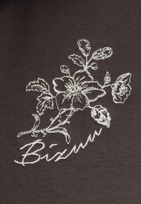 Bruine stof met een witte geborduurde bloemenpatroon en de tekst "Bizuu." Heeft ingewikkelde details van bloemen en bladeren.