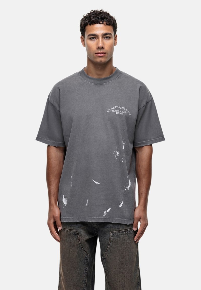 Przyduża szara koszulka z bawełny z okrągłym dekoltem, wyblakły wzór i białe plamy farby na przodzie i rękawach.