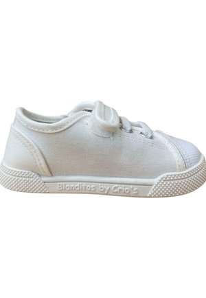 Zapatilla de lona blanca con suela de goma texturizada, puntera redondeada y diseño de cordones. Presenta una marca en el lateral y un cuello acolchado.