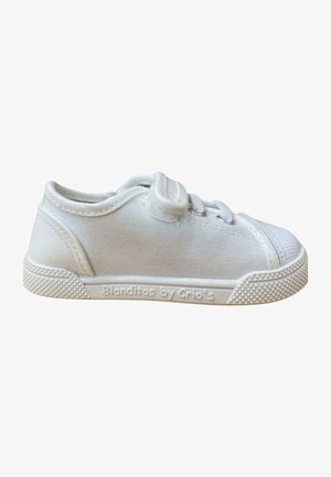 Zapatilla de lona blanca con suela de goma texturizada, puntera redondeada y diseño de cordones. Presenta una marca en el lateral y un cuello acolchado.