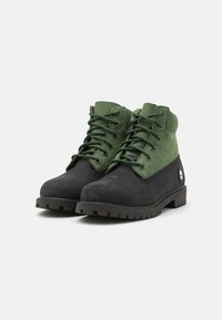 Mustad mustaad ja rohelised ankle-bootsid, sametülemäega, ümmarguse varbaga, vastupidava kummist tallaga, nööbiga disain ja logo detail külgedel.