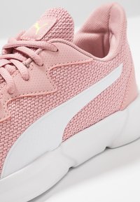 Różowe siateczkowe sneakersy z teksturowaną cholewką, białymi akcentami i płaskimi sznurowadłami. Posiadają wyściełany kołnierz oraz elastyczną białą podeszwę.