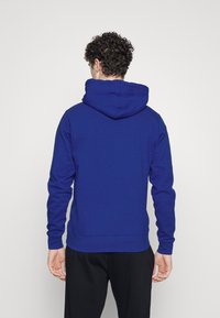 Felpa blu con cappuccio, polsini e fondo a coste. Tessuto morbido, vestibilità classica, con tasca a marsupio. Adatta per un look casual.