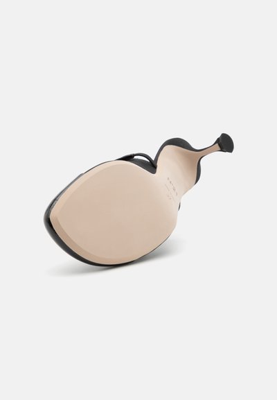 Črni visoki petni čevlj s gladkim usnjem zgornjega dela, s koničastim nosom in golim usnjenim podplatom. Opremljen je z elegantno silhueto in minimalno dodatno opremo.