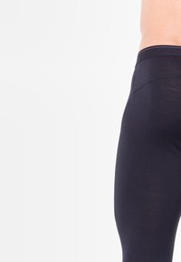 Zwarte leggings met een aansluitend ontwerp, een gladde textuur en een elastische tailleband, voorzien van versterkte stiksels langs de naden.