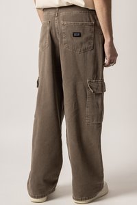 Braune Cargo-Hosen mit lockerer Passform, die große Seitentaschen und ein Markenpatch auf der Rückseite haben. Hergestellt aus strapazierfähigem Baumwollmaterial.