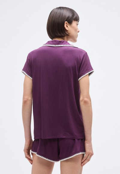 Lila pamut pizsamaszett rövid ujjú felsővel és rövidnadrággal, fehér hullámos szegéllyel a galléron és az alján. Puha, laza szabás.