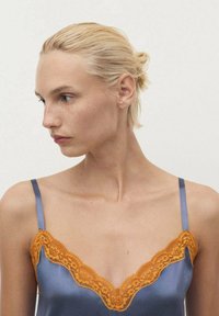 Camisón de satén en azul marino, con un borde de encaje naranja a lo largo del escote y tirantes ajustables, textura suave y diseño delicado.