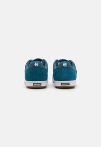 Teal suede sneakers with mesh accents, white rubber sole, and Michelin logo on the heel. Rounded design with a low-cut silhouette.
