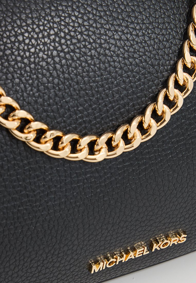 Borsa a mano in pelle nera con superficie testurizzata, accentuata da una catena dorata e un'etichetta con logo. Il design è compatto e strutturato.