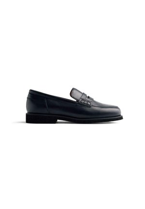 Mocassino in pelle nera con profilo basso, superficie liscia e una piccola striscia decorativa sulla parte superiore. Presenta una suola testurizzata.