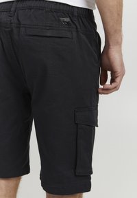 Shorts cargo noirs en coton mélangé. Dotés de poches latérales, d'une poche arrière et d'une coupe décontractée avec des coutures visibles.