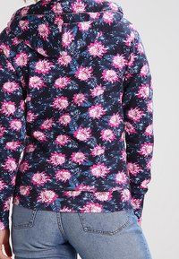 Felpa con cappuccio caratterizzata da uno sfondo blu navy scuro con vivaci motivi floreali rosa e foglie verdi, realizzata in un tessuto morbido e testurizzato.