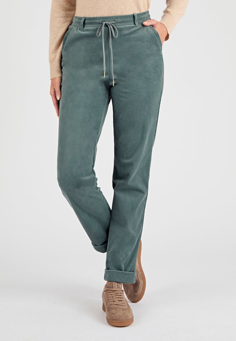 Pantaloni a coste in verde tenue con vita regolabile, tasche laterali e orli arrotolati. Texture morbida con motivo a coste verticali.