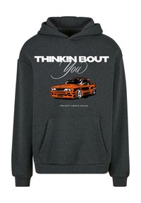 Siva dukserica s kapuljačom koja ima prednji džep. Sadrži grafiku narančastog automobila i bijeli tekst koji kaže "THINKIN BOUT You" i "I BELIEVE THERE'S HEAVEN."