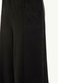 Schwarze Jogginghosen mit einer Seitentasche und strukturierten "CASUAL IDENTITY"-Details entlang des Beins, gefertigt aus weichem, glattem Stoff.